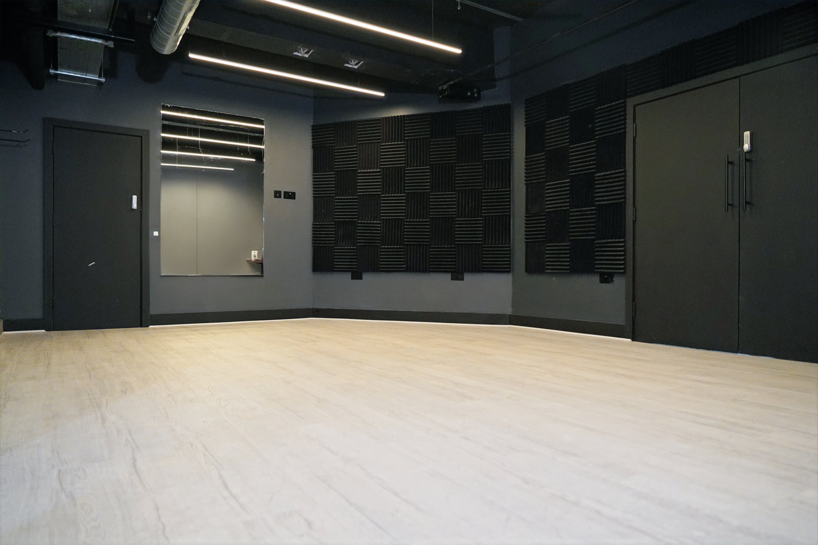 Private practice room with a mirror, wood-effect floor and acoustic wall panels